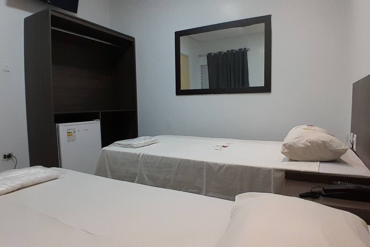 Habitación de hotel con dos camas, un escritorio pequeño, un espejo y un armario.