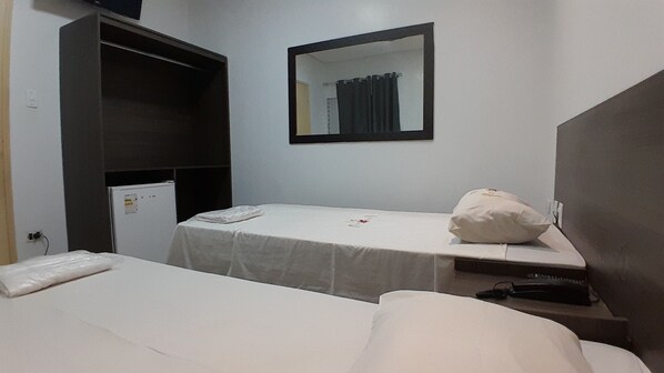Habitación de hotel con dos camas, un escritorio pequeño, un espejo y un armario.