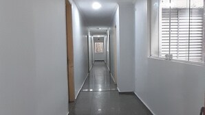 A long, narrow hallway with white walls and a tiled floor. There is a fire extinguisher mounted on the wall on the right side. - Center plaza hotel (Sao Paulo)