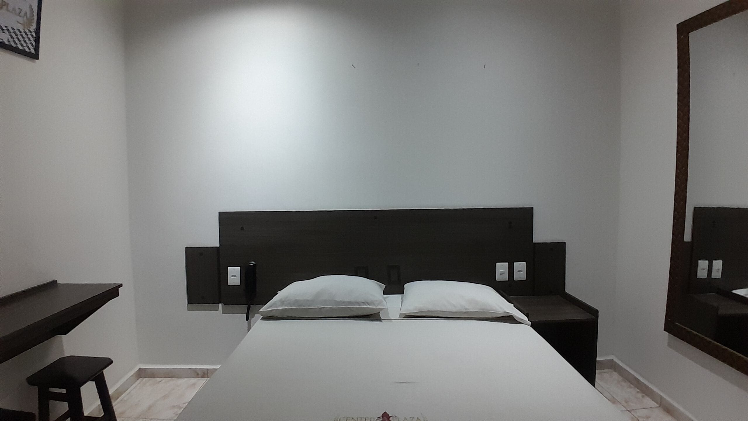 A hotel room with a single bed, a small desk, and a mirror on the wall.