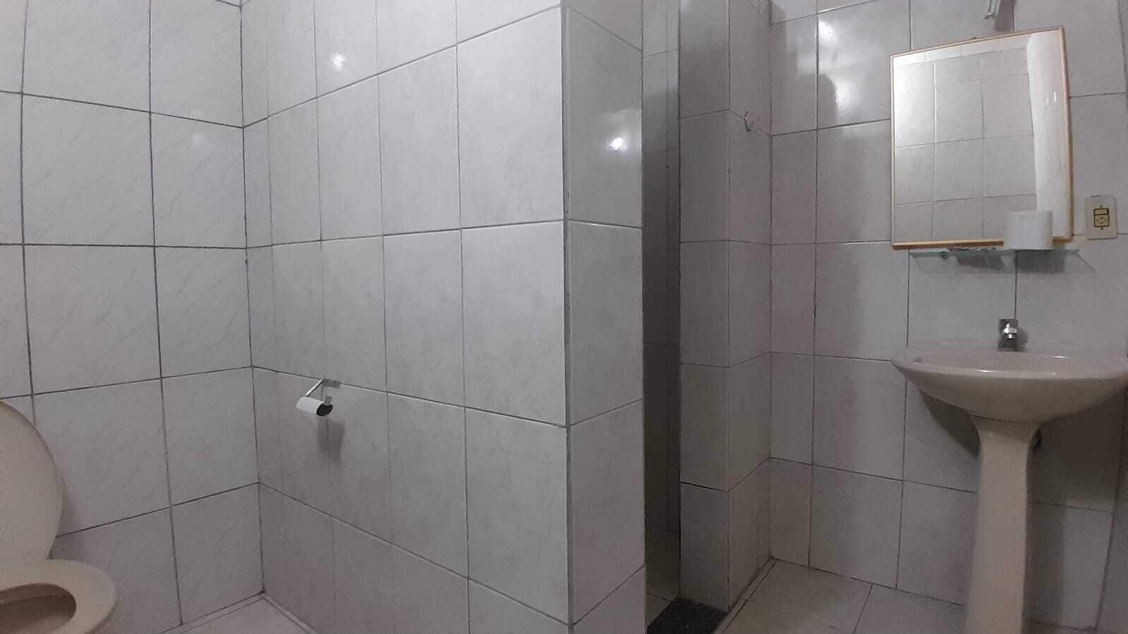 A bathroom with white tiles, a toilet, a sink, and a mirror.