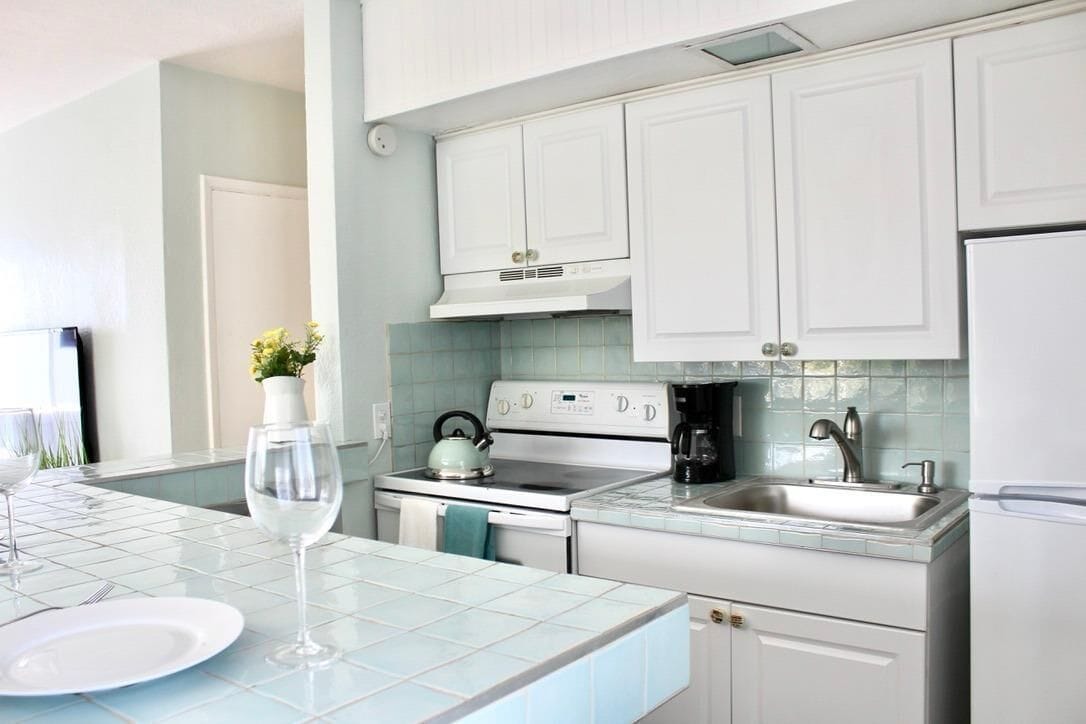 A modern kitchen with white cabinets, a stove, and a sink.