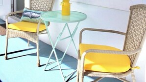 A room with two wicker chairs, a small glass table, and a yellow vase with flowers. There are two wall-mounted turtle sculptures. - Seabreeze Suite Studio on Hollywood Beach (Hollywood)