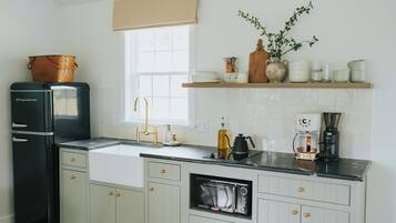 A kitchen with a black refrigerator, a sink, a microwave, and a coffee maker.