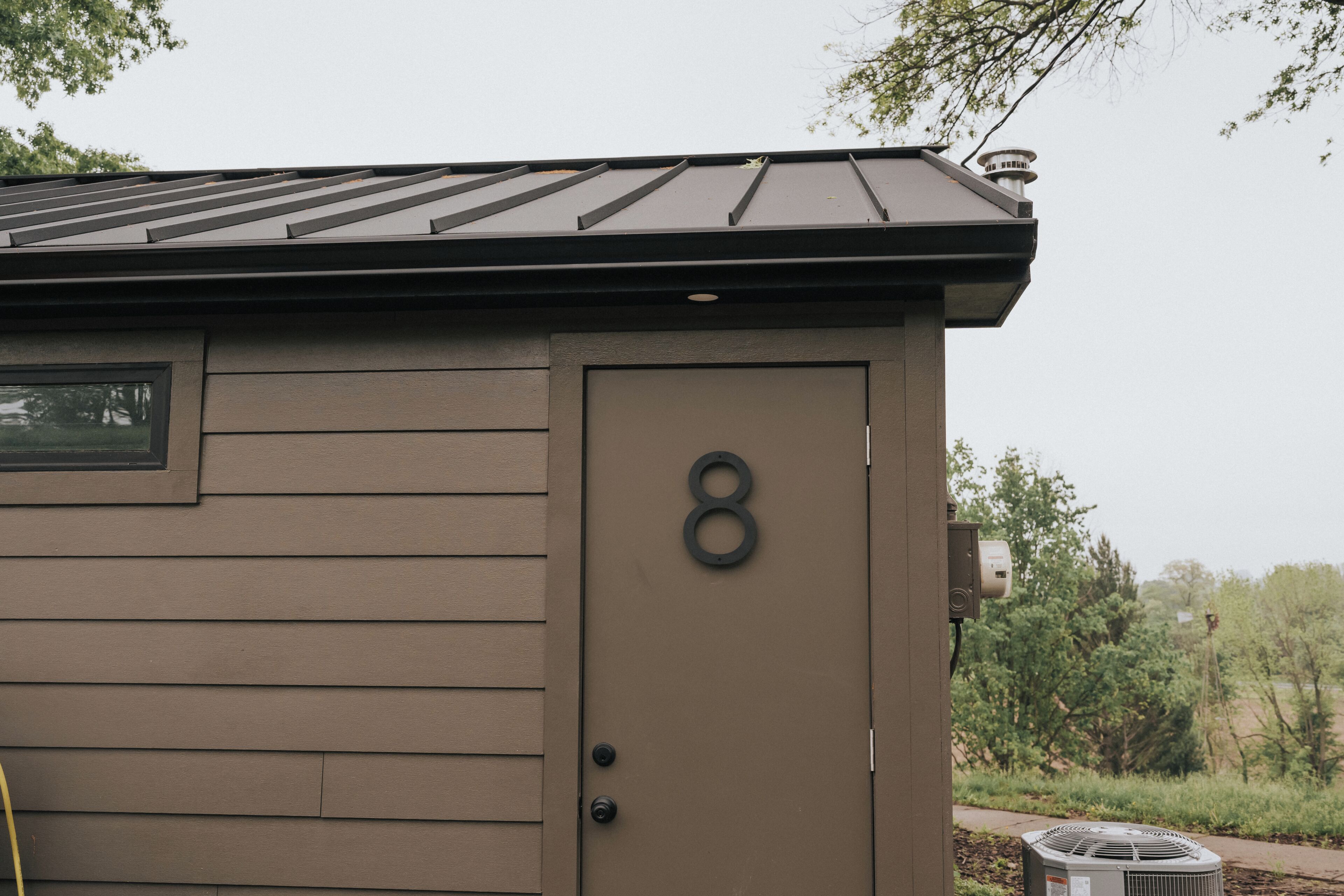 A brown building with a flat roof and a door marked with the number 8.