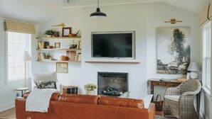 Una sala de estar con chimenea, televisor y mobiliario de mimbre.