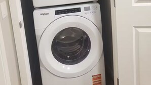 A compact laundry room with two Whirlpool washing machines stacked vertically. - Family Retreat 2BDR 2BT / Remote Work Ready / Lake Access / Games / South Health (Calgary)