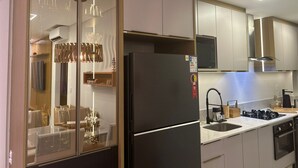 Et moderne køkken med et sort køleskab, rustfrie stål hvidevarer og en glasvæg, der adskiller spiseområdet.