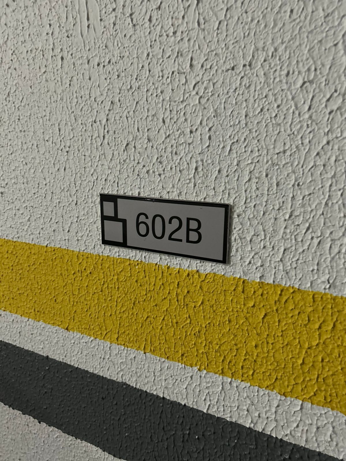 En væg med struktur, hvor et skilt viser nummeret 602B.