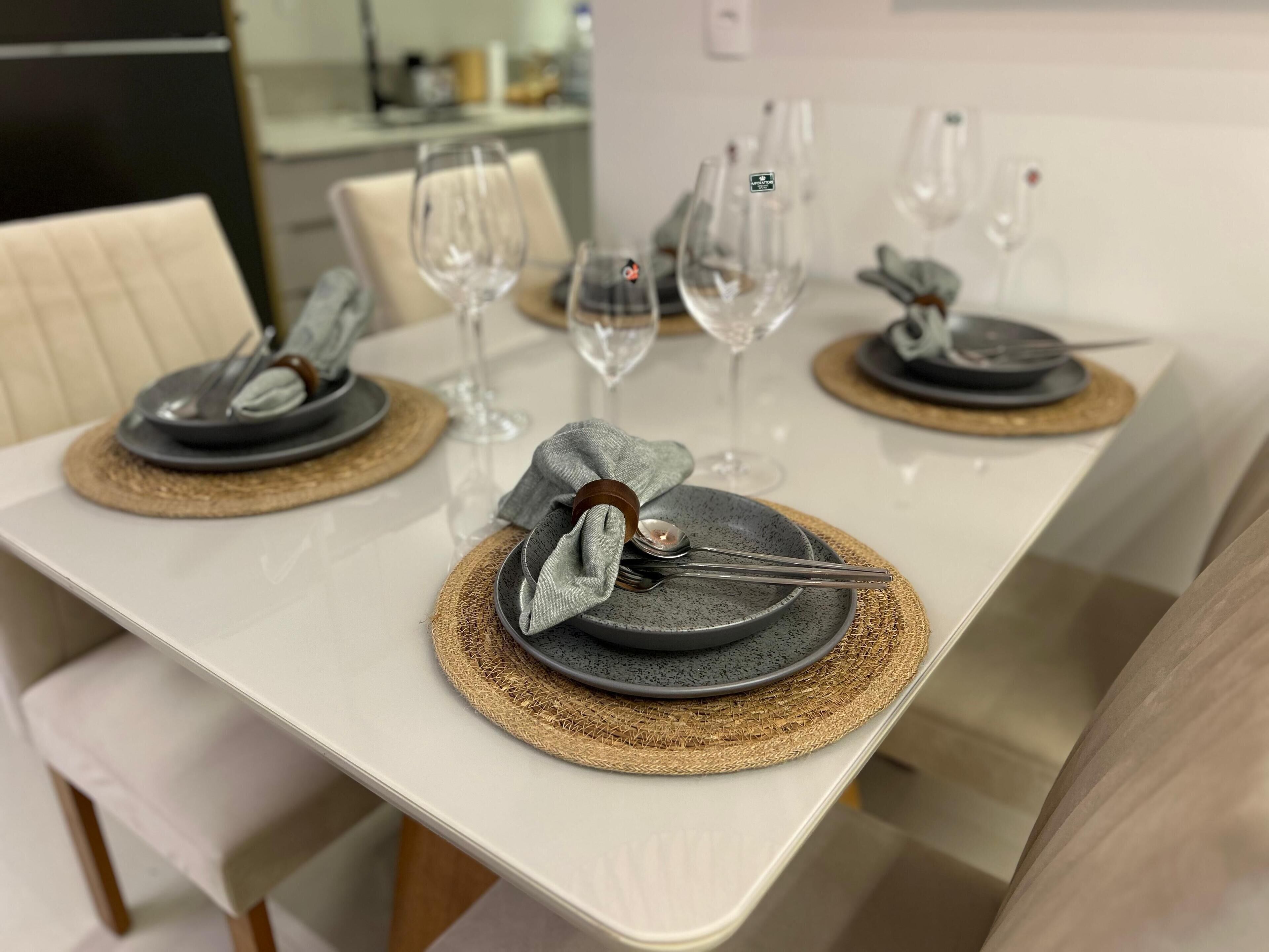 Uma mesa de jantar posta com pratos, talheres e copos de vinho.