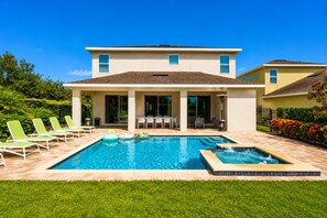 A two-story house with a swimming pool, outdoor seating, and a patio area.
