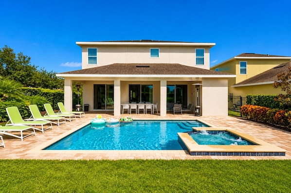 A two-story house with a swimming pool, outdoor seating, and a patio area.