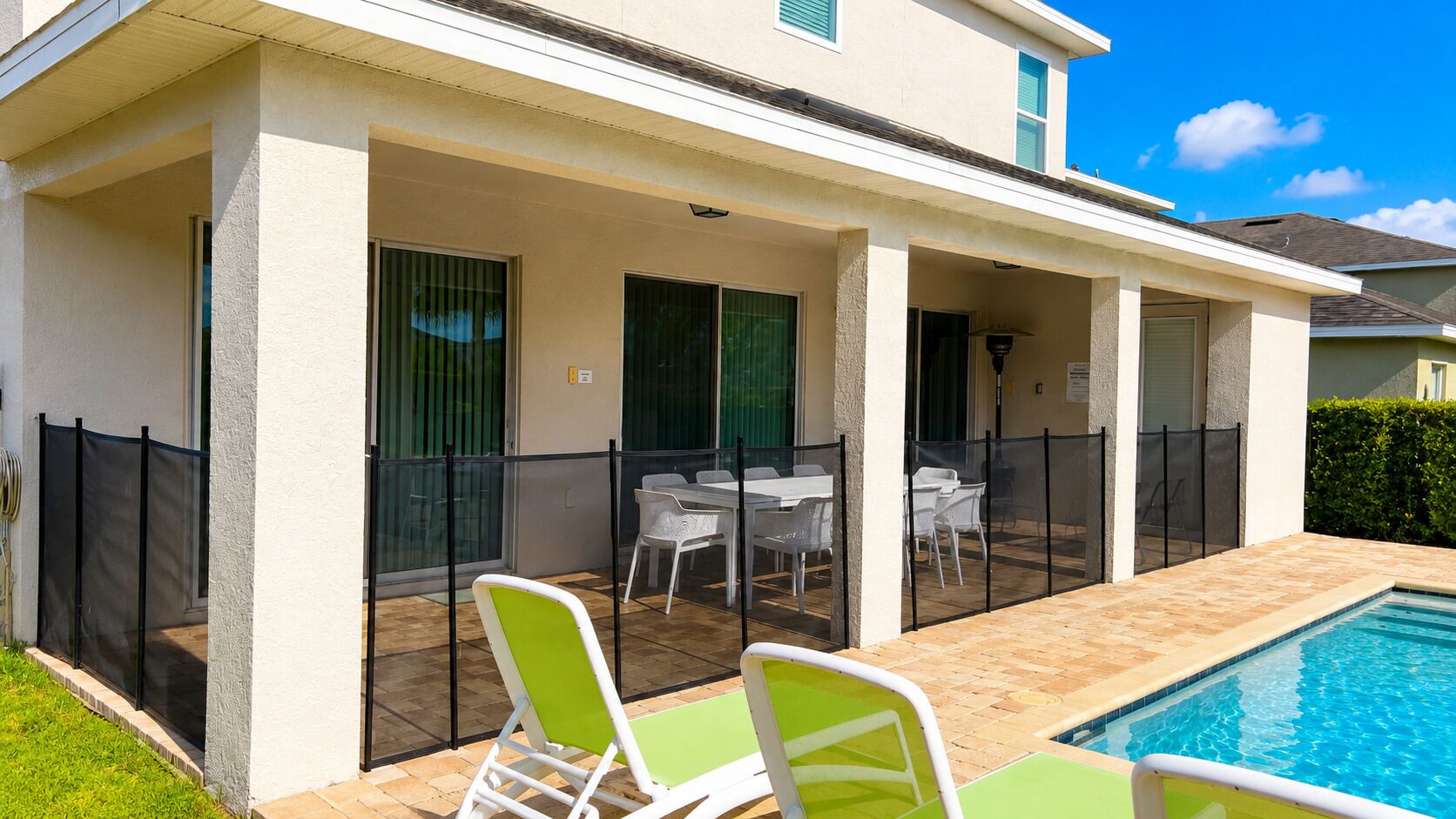 A covered outdoor area with a pool, chairs, and tables.
