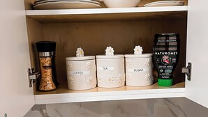 Una cocina con encimera de mármol, cafetera, tostadora y especiero.
