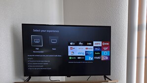 Ein Flachbildfernseher an einer weißen Unterhaltungseinrichtung, darunter ein Ablagebereich.