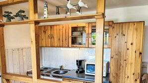 A compact kitchen with wooden cabinets, a sink, a stove, a microwave, and a coffee maker. - Apartment Emma by Interhome (Trassenheide)