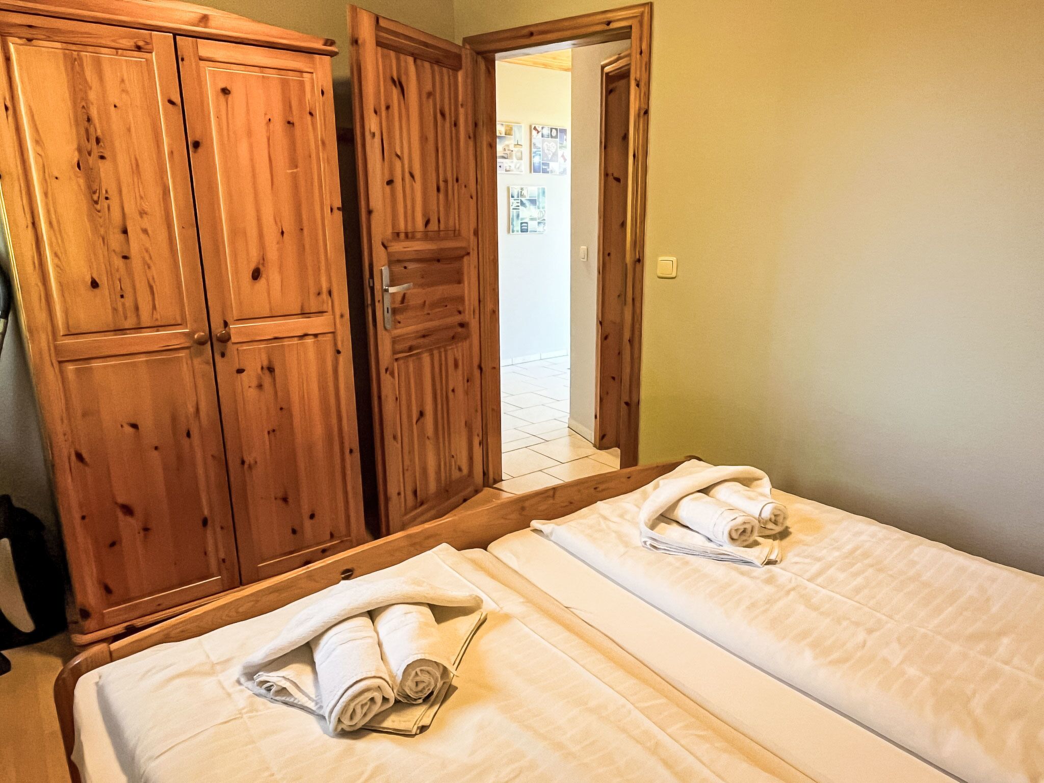 Een hotelkamer met twee bedden, houten kasten en uitzicht op het exterieur.