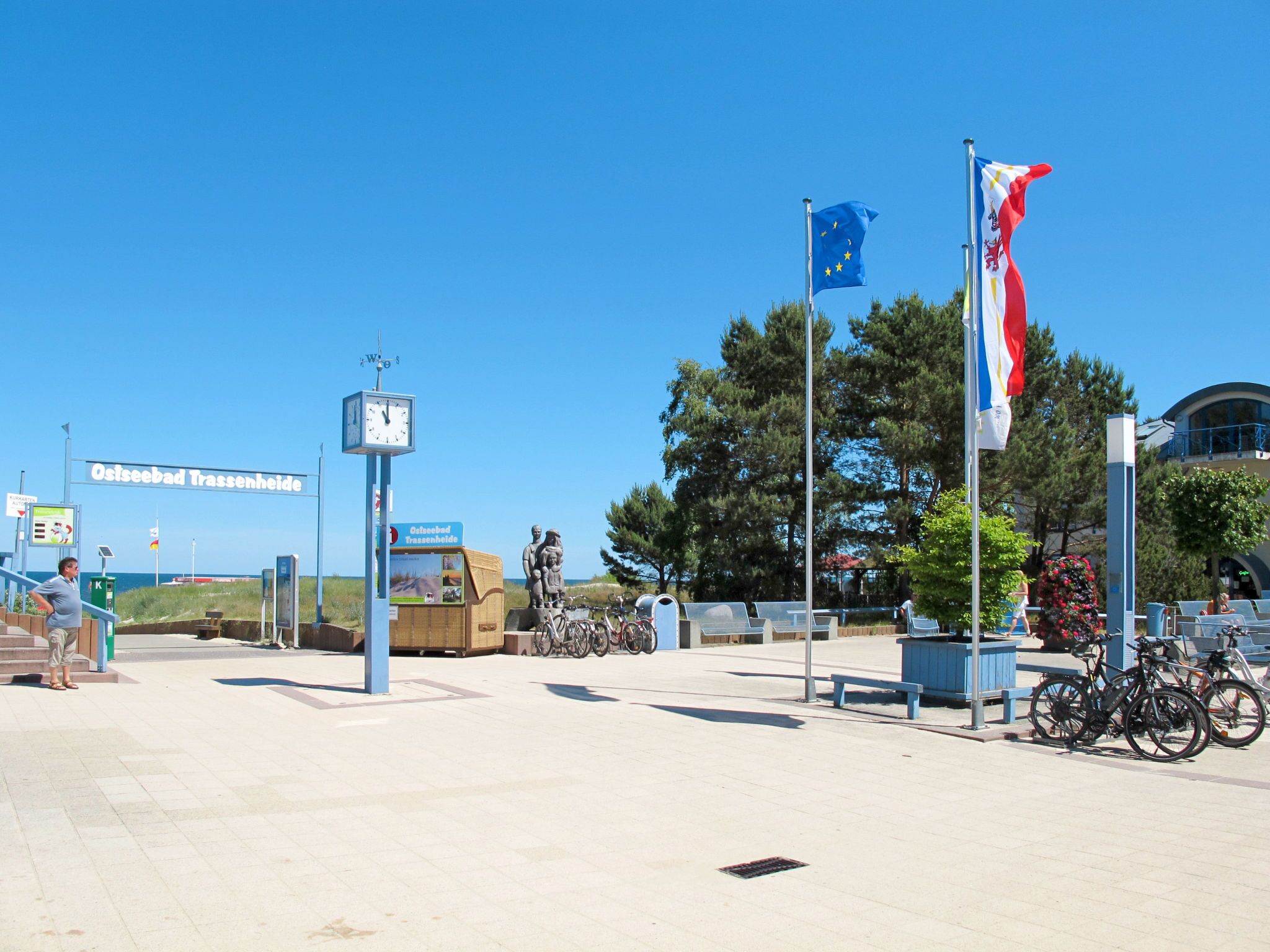 A public square with a clock, flags, and bicycles.