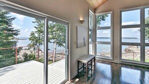 Une pièce dotée de grandes fenêtres donnant sur un lac et une terrasse.