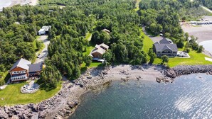 Une propriété située sur la côte, comprenant plusieurs maisons, un littoral rocheux et offrant une vue dégagée sur l’eau.