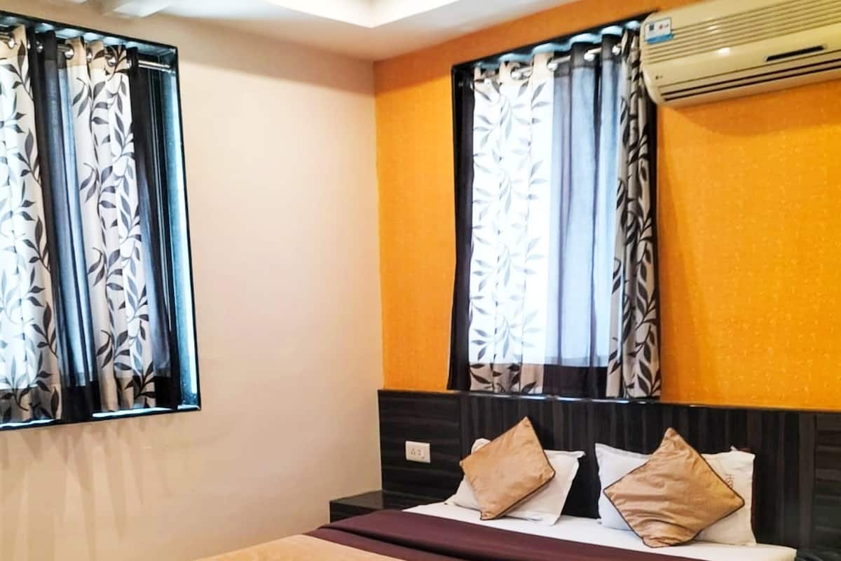 Une chambre d’hôtel moderne avec un grand lit, une tête de lit et un appareil de climatisation.