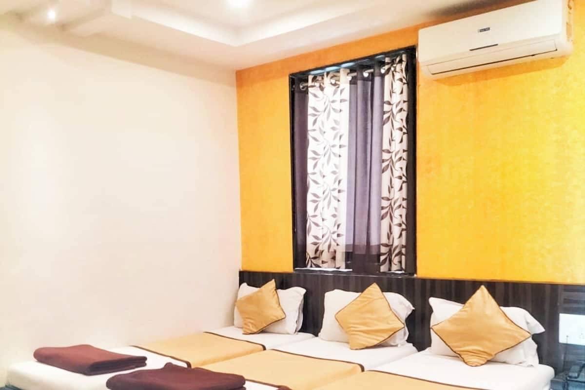 Une chambre d’hôtel avec un grand lit, une fenêtre avec des rideaux, un climatiseur et un ventilateur de plafond.
