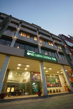 A hotel named 'One Earth Central Park' with a modern facade, large windows, and a reception area with potted plants. - Hotel Surya Residency (Amritsar)