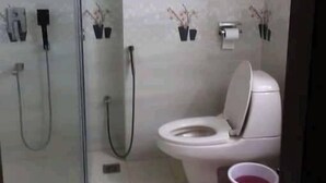 Een badkamer met een toilet, een douche en twee wandfonteintjes.