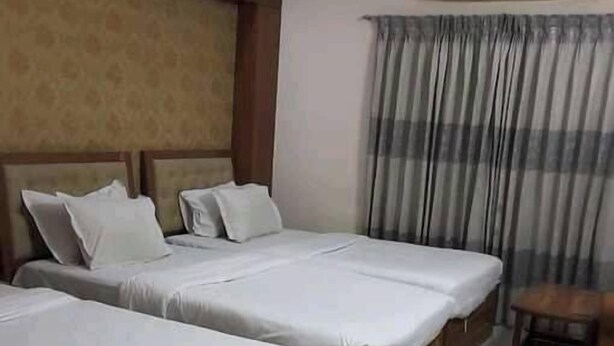 Een hotelkamer met twee bedden, een houten hoofdbord, een klein houten tafeltje en een airconditioner aan de muur.