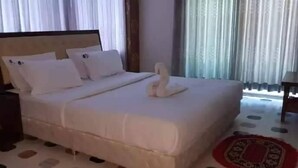 Een hotelkamer met een groot bed, een nachtkastje en een raam met gordijnen.