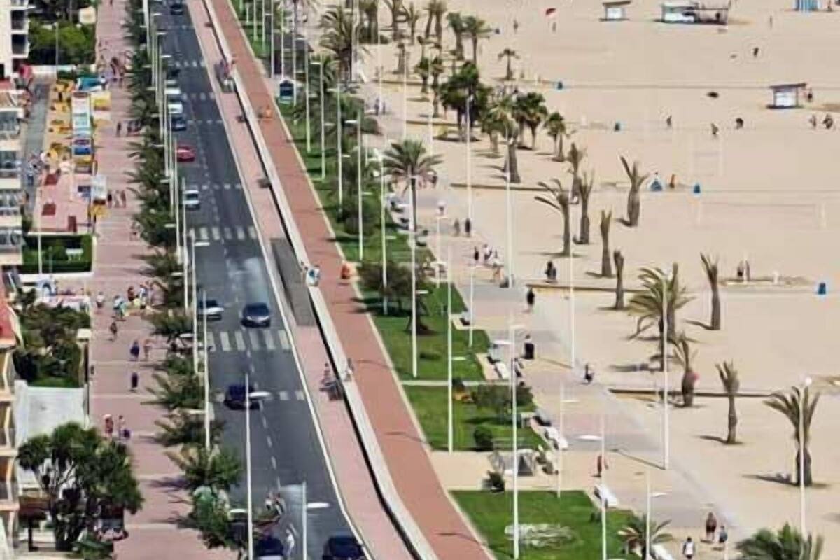 Una carretera costera con una playa a un lado y una hilera de edificios al otro.