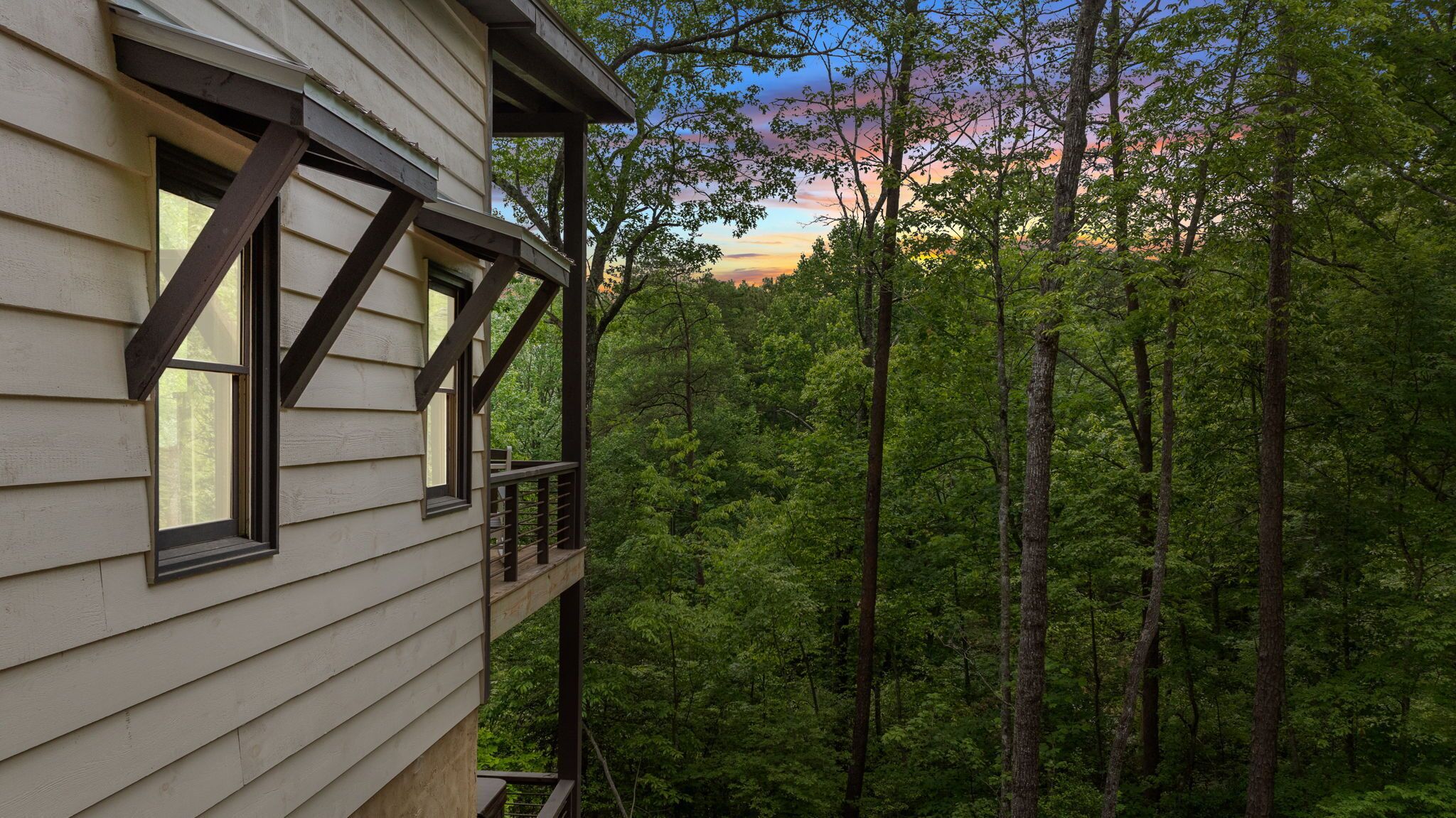 A house with a balcony overlooking a dense forest.
