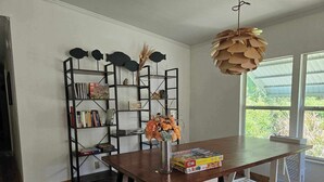 Une cuisine moderne avec une table en bois, une étagère décorative en forme de poisson et un luminaire suspendu.