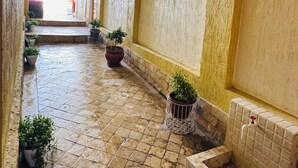 Egy folyosó, csempézett padlóval, virágtartókban elhelyezett növényekkel és csempézett ülősarokkal.