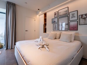 Relax in a serene space with a large bed, sheer curtains, and a shelving unit.