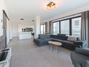 Relax in this stylish living space with a large sofa, flat-screen TV, and kitchenette.
