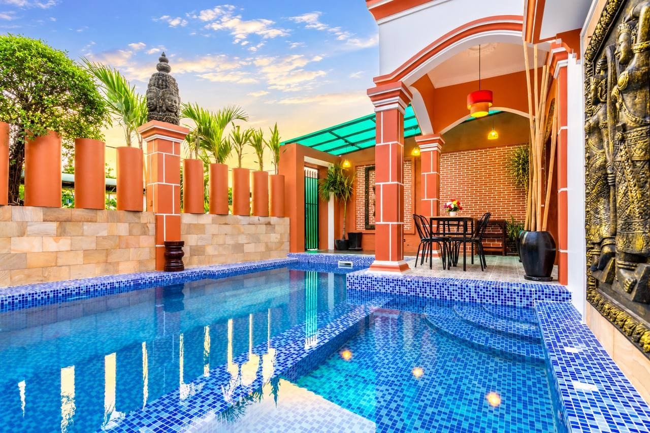 A swimming pool with tiled edges, a statue, and a brick wall.