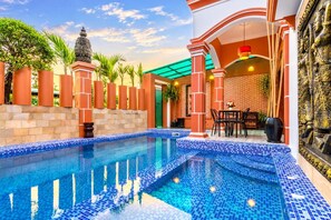A swimming pool with tiled edges, a statue, and a brick wall.
