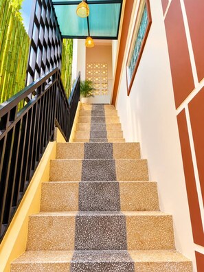 A staircase with alternating beige and dark tiles, a black railing, and a wall with a geometric pattern. - 855 Villa Siem Reap  (Siem Reap)