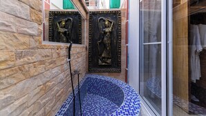 A stone wall with a blue-tiled bathtub, a window with a view of buildings, and a door with a green shutter. - 855 Villa Siem Reap  (Siem Reap)