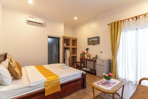 A hotel room with a bed, a desk, a chair, a table with a floral tablecloth, and a window with curtains. - 855 Villa Siem Reap  (Siem Reap)
