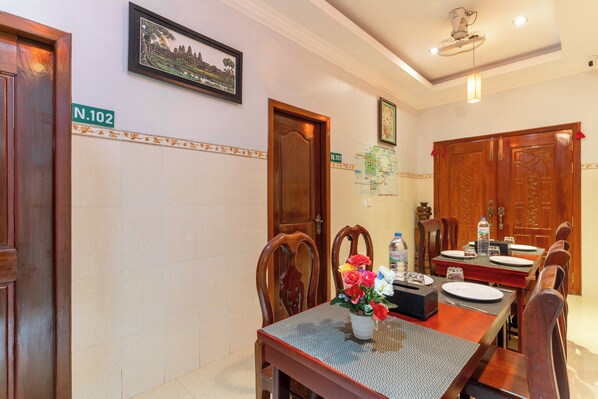 A dining area with a wooden table, chairs, a vase of flowers, and a map on the wall. - 855 Villa Siem Reap  (Siem Reap)