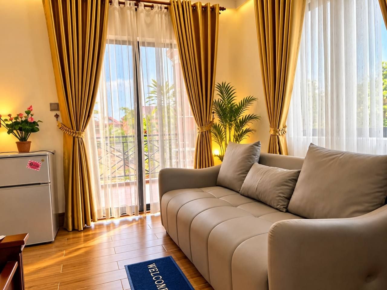 A living room with a sofa, a small table, a refrigerator, and a plant.