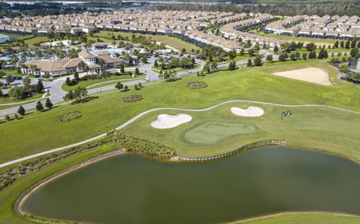 Vista aerea di una zona residenziale con case, un campo da golf e uno stagno.
