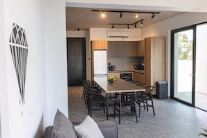 A modern kitchen with a dining area, a large window, and a built-in air conditioning unit.