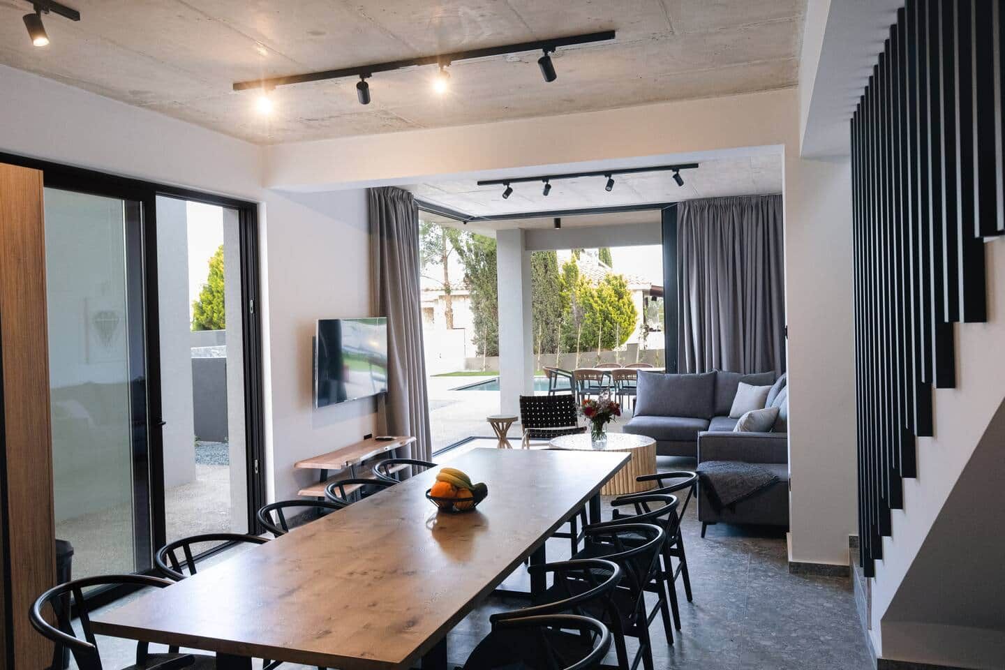 A modern interior with a dining area, a sofa, and a TV.