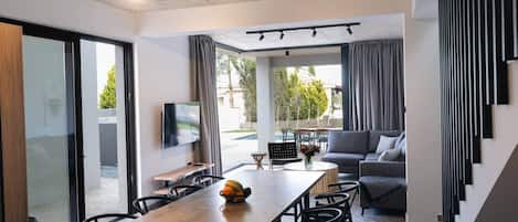 A modern interior with a dining area, a sofa, and a TV.