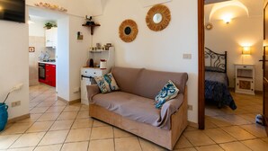 A cozy living room with a sofa, a TV, and a kitchen in the background. - Terrazza Bella Vista by Interhome (Lingueglietta)