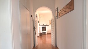 A hallway with white walls, a tiled floor, and a wooden door on the left. - Villa with large garden (Marina di Campo)