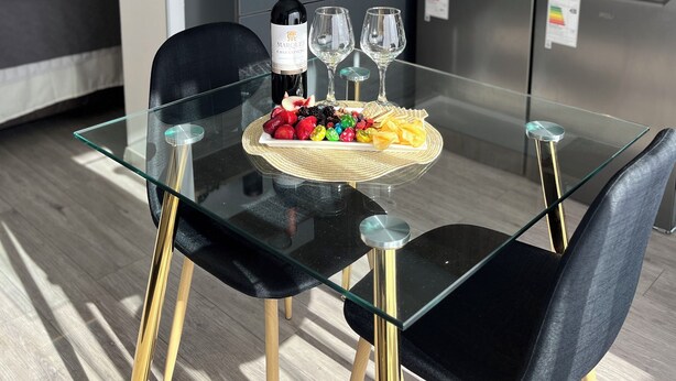 Una cocina moderna con armarios de madera, un refrigerador de acero inoxidable y una mesa de vidrio con dos sillas.